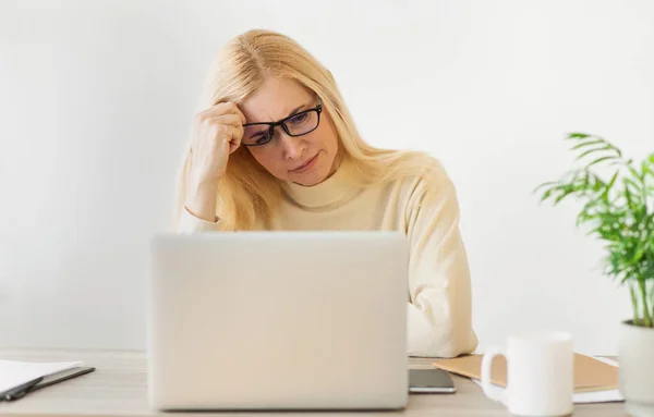 Mujer aburrida trabajando en el ordenador portátil y mirando fijamente a la pantalla — Foto de Stock