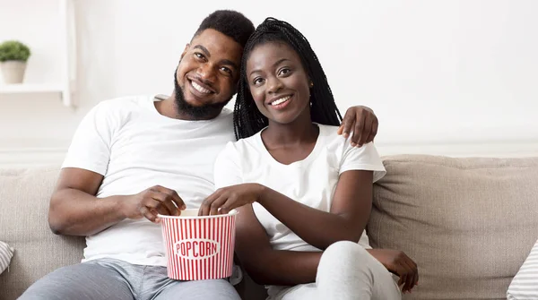 Casal negro romântico comendo pipocas e assistindo filme em casa juntos — Fotografia de Stock