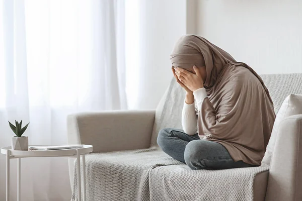 Depresso ragazza araba in hijab piangendo sul divano a casa — Foto Stock