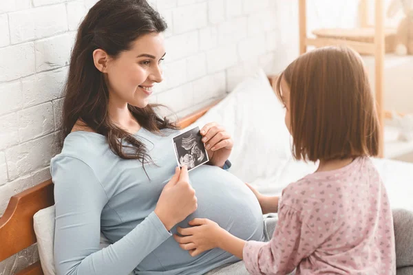 Madre embarazada mostrando ecografía a su hija — Foto de Stock