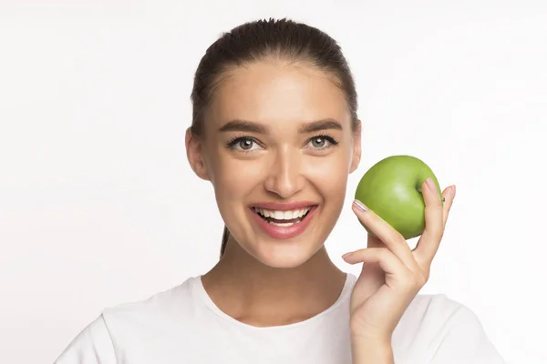 Millennial flicka håller Apple ler mot kameran stående i Studio — Stockfoto