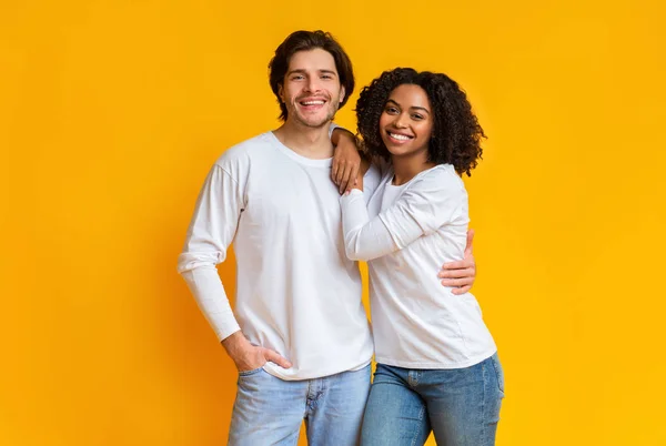 Portret uśmiechniętej mieszanej pary pozującej na żółte tło w studio — Zdjęcie stockowe