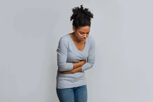 Молода чорна жінка має менструальний біль у животі — стокове фото