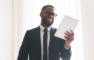 Dijital tablet kullanan neşeli siyah işadamı, ofis içi