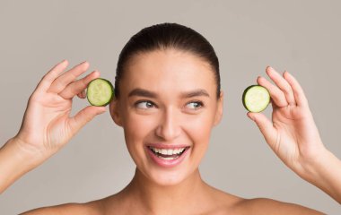 Sağlıklı eğlence. Elinde salatalık dilimleri tutan neşeli bir kadın.