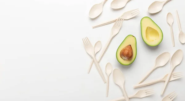 Helften van avocado en eco lepels en vorken op witte achtergrond — Stockfoto