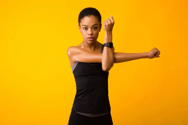 Afro ragazza che fa Deltoid braccio allungare esercizio su sfondo giallo — Foto Stock