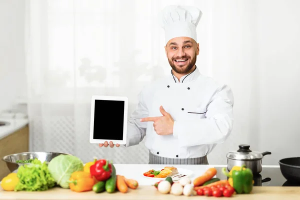 Cuoco uomo tenendo compressa puntando dito sullo schermo in cucina — Foto Stock