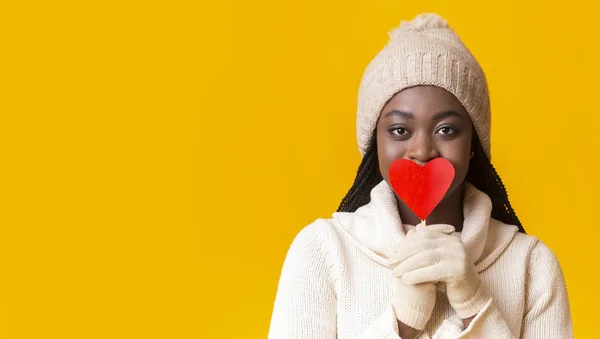 Прекрасна жінка, що покриває рот карткою у формі червоного серця — стокове фото