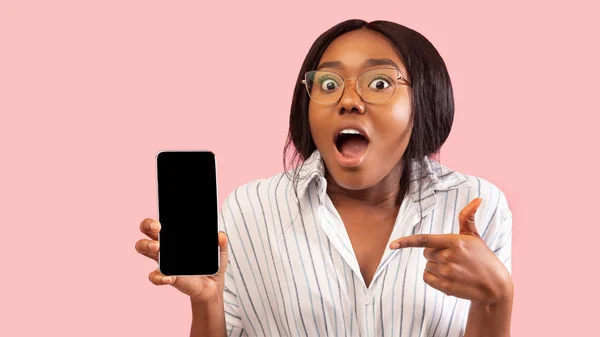 Возбужденная афроамериканская девушка держит телефон указывая пальцем, студия, макет — стоковое фото