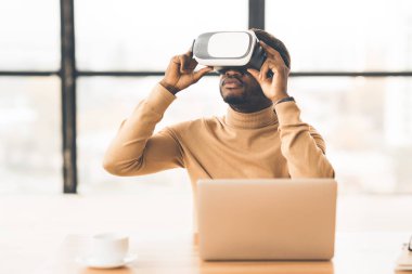 Afro iş adamı evde artırılmış gerçeklik gözlüğü takıyor.