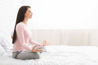 Sakin kadın evde yoga yapıyor, yandan bakıyor.