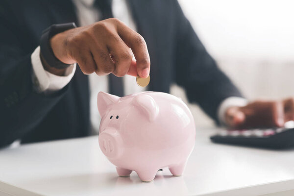 Cropped of businessman putting coin into piggy bank