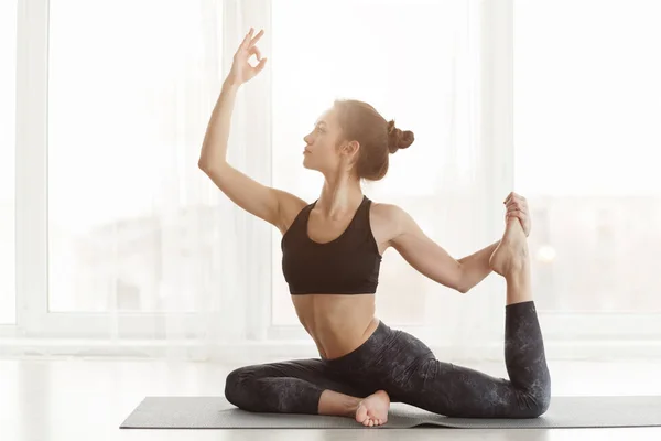 Smal kvinna som tränar yoga, stretchar på mattan — Stockfoto