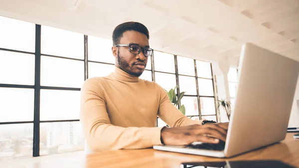 Концентрированный афроамериканец, работающий с ноутбуком — стоковое фото