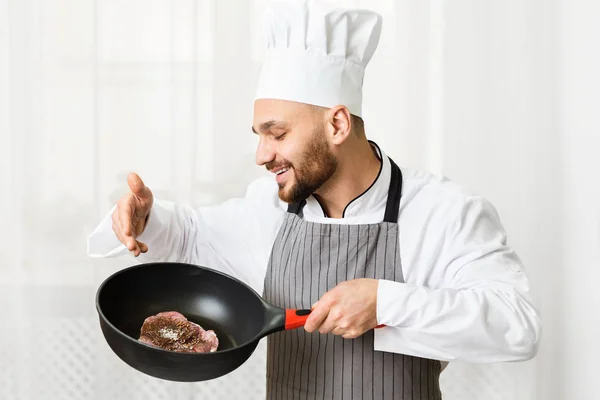 Šéfkuchař drží pánev s masovým steakem stojící v kuchyni — Stock fotografie