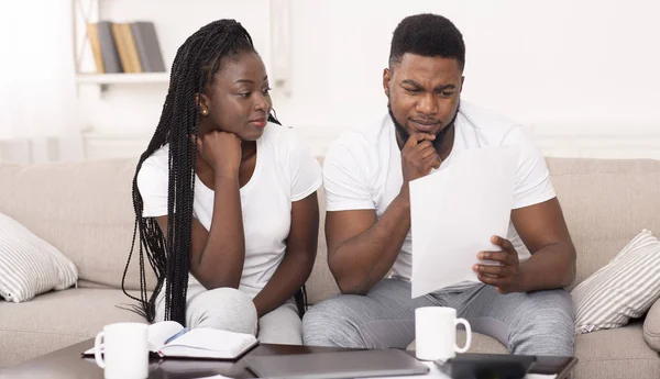 Schwarzes Ehepaar liest Zeitung zu Hause auf Couch — Stockfoto