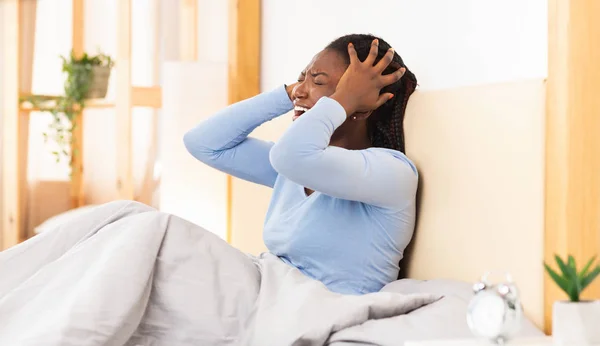 Afro Lady gritando cobrir as orelhas sentado na cama interior — Fotografia de Stock