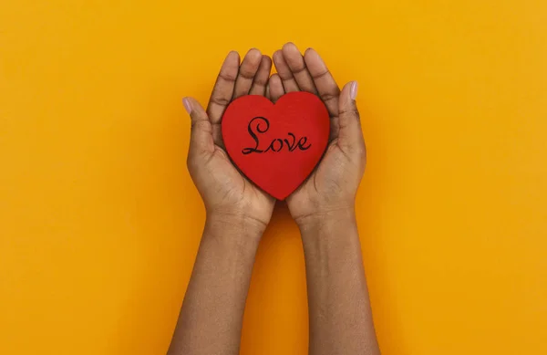 Coração de madeira com amor inscrição em mãos de mulheres americanas africanas — Fotografia de Stock