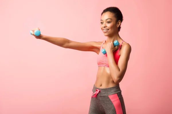 Black Woman Holding Dumbbells Doing Boxing Exercise Over Pink Background — 스톡 사진