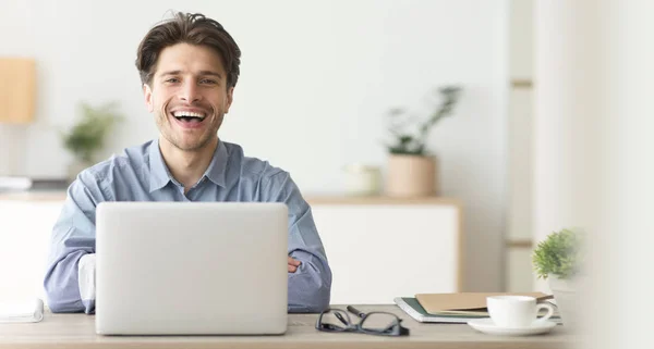 Feliz empleado sonriendo en la cámara mientras trabaja en el ordenador portátil en la oficina — Foto de Stock