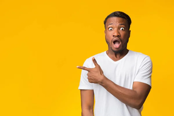 Verrast zwarte man wijzend vinger naast staande in de studio — Stockfoto