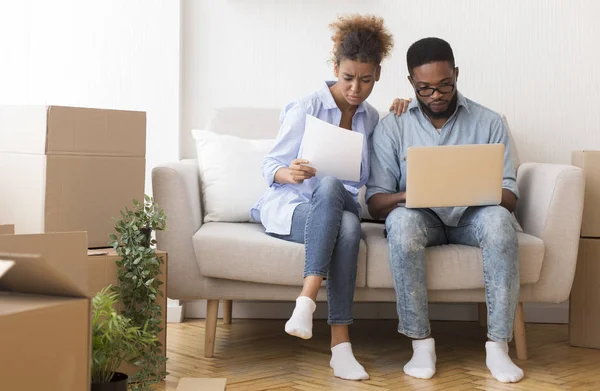 Serious Black Couple Reading Ownership Papers Sitting On Sofa Indoor — 스톡 사진