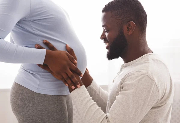 Felice marito toccando la sua pancia moglie incinta a casa — Foto Stock