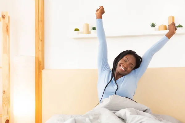 Щаслива леді розтягування руки прокидаючись в ліжку вдома — стокове фото