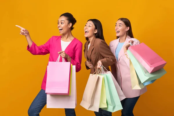 Tre upphetsade damer håller Shopper väskor Peka Finger, gul bakgrund — Stockfoto