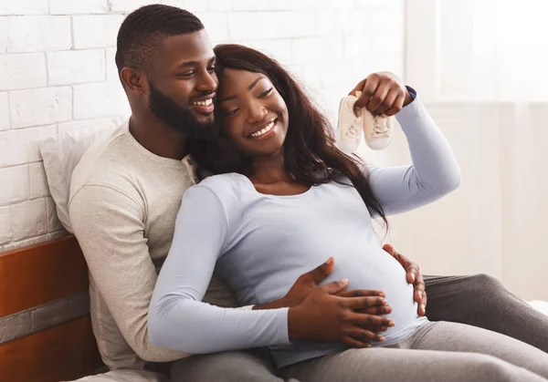 Беременная женщина и ее муж смотрят на маленькие сапожки — стоковое фото