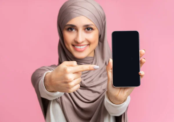 Gadis Muslim memegang smartphone dengan layar hitam dan menunjuk itu — Stok Foto