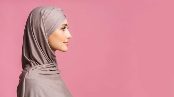 Profilportræt af beskeden muslimsk kvinde i hijab over lyserød baggrund - Stock-foto