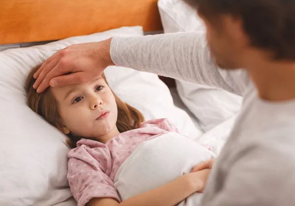 Man checking his ill daughter temperature, touching his forehead — Stock Photo, Image