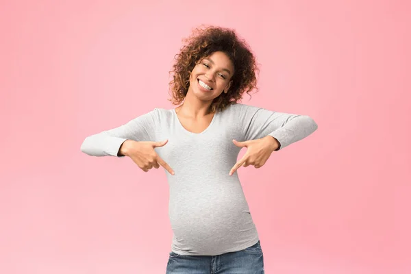 Guardi qui. Donna afro incinta positiva che punta il dito contro la pancia — Foto Stock