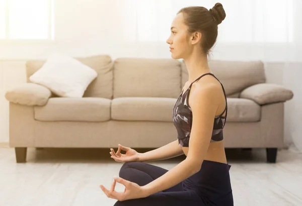 Jovem mulher meditando em ambiente doméstico, praticando ioga — Fotografia de Stock