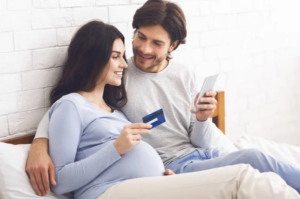 Terhes pár online vásárlás okostelefonnal és hitelkártyával otthon — Stock Fotó