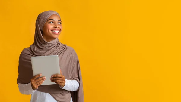 Negro musulmán chica en hijab celebración digital tablet y mirando a un lado —  Fotos de Stock