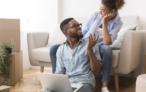 Africano casal americano falando usando laptop sentado em novo apartamento — Fotografia de Stock