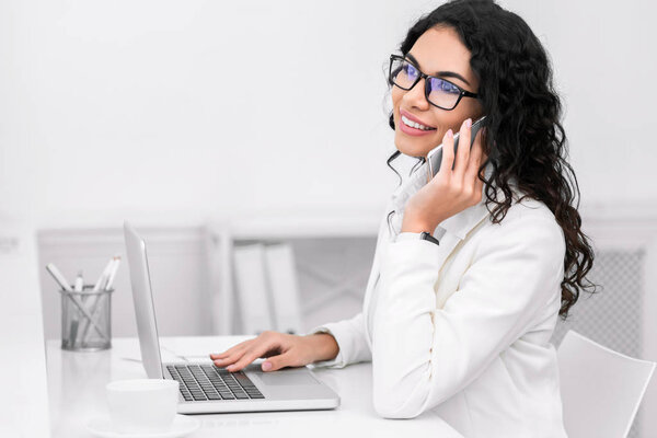 Латиноамериканка разговаривает по телефону, работает в офисе
