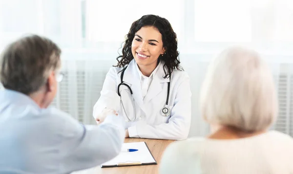 Glückliches reifes Paar beim Händeschütteln mit seinem Betreuer — Stockfoto