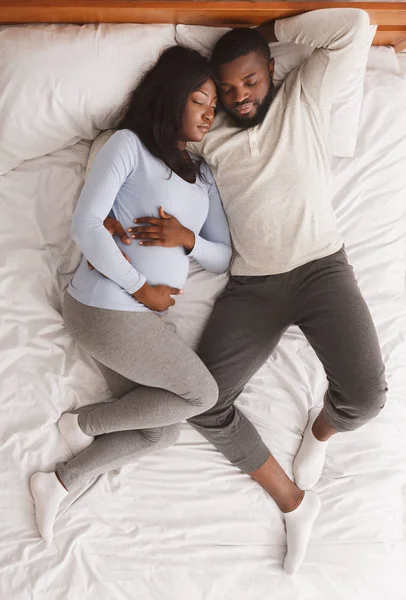 Afrikaans amerikaans verwachting paar dutten in bed, top view — Stockfoto