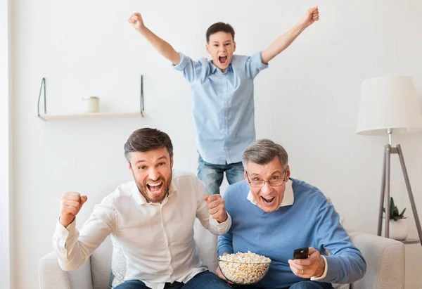 Familia masculina viendo deportes en la televisión celebrando la victoria en casa — Foto de Stock