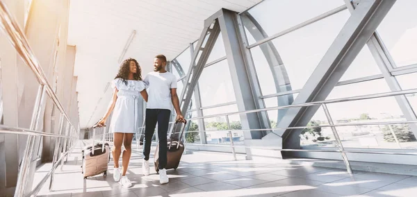De camino a la luna de miel. Recién casados africanos caminando con maletas en la terminal del aeropuerto, espacio vacío — Foto de Stock
