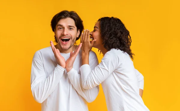 Interrazziale coppia pettegolezzi insieme su sfondo giallo — Foto Stock