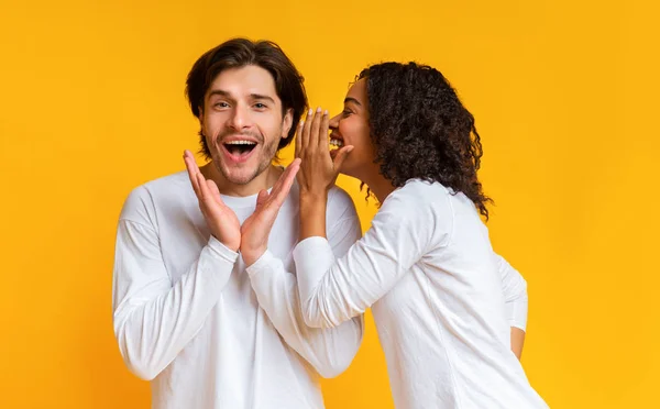 Interraciale paar roddelen samen over gele achtergrond — Stockfoto