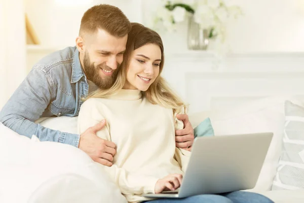 Millennial couple web surfing on laptop at home
