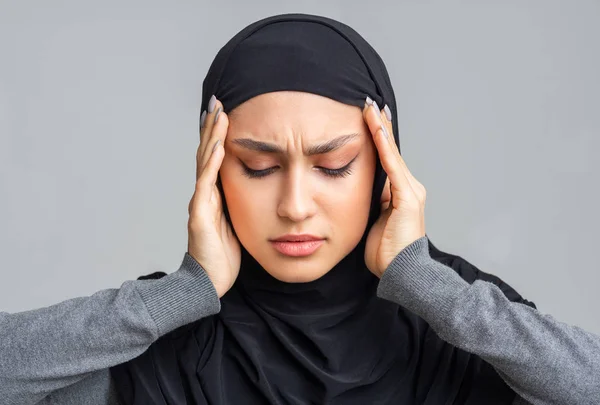 Арабская женщина в хиджабе трогает виски, страдает головной болью и мигренью — стоковое фото
