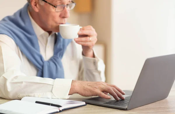 Ανώτερος άνθρωπος στο Laptop πίνοντας καφέ εργασίας κάθεται στο γραφείο — Φωτογραφία Αρχείου