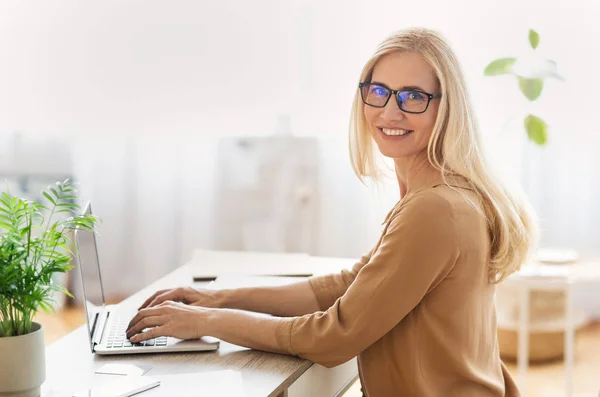 Sukces bizneswoman siedzi na laptopie i uśmiecha się do kamery — Zdjęcie stockowe